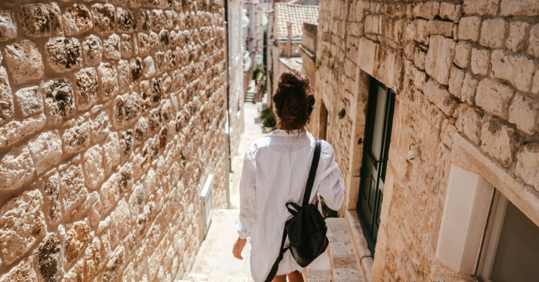 Young girl walking through ancient narrow streets on a beautiful summer day in Croatia south Europe